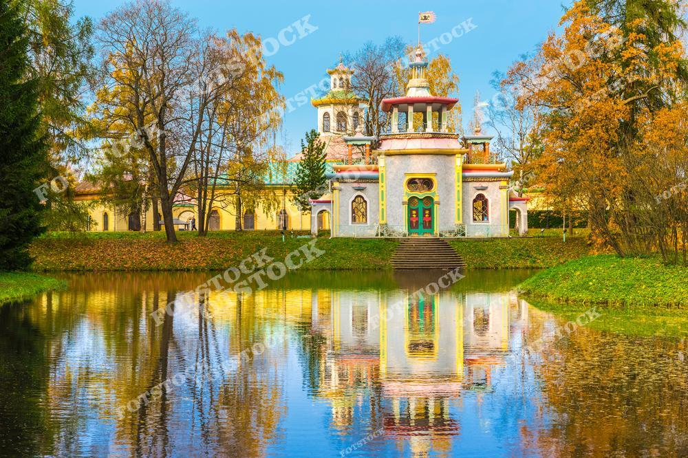 На снимке изображен Китайский павильон в Александровском парке Царского Села. Этот архитектурный ансамбль, выполненный в китайском стиле, был создан для украшения парка и придания ему восточного колорита. Зеркальное отражение здания в водах пруда добавляет картине симметрии и спокойствия. Осенние листья и голубое небо создают яркий контраст, подчеркивая уникальность места и красоту осеннего Санкт-Петербурга.